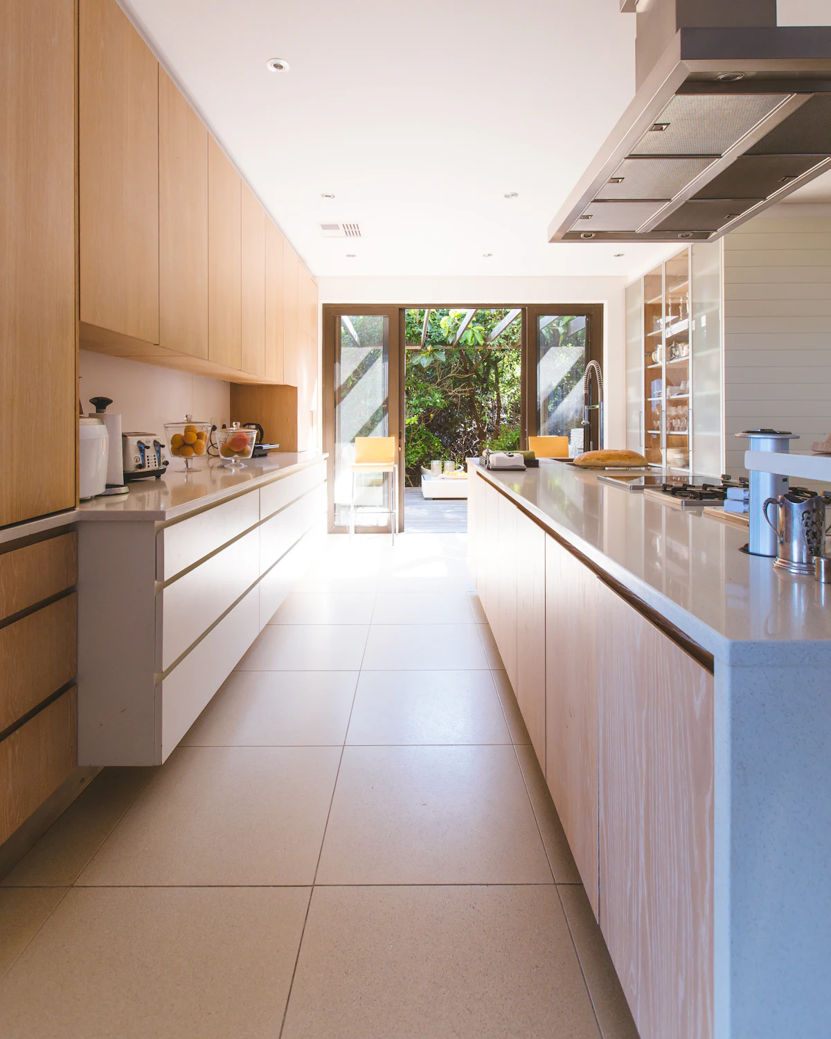 A bright, spotless white kitchen with sunlight down the hall