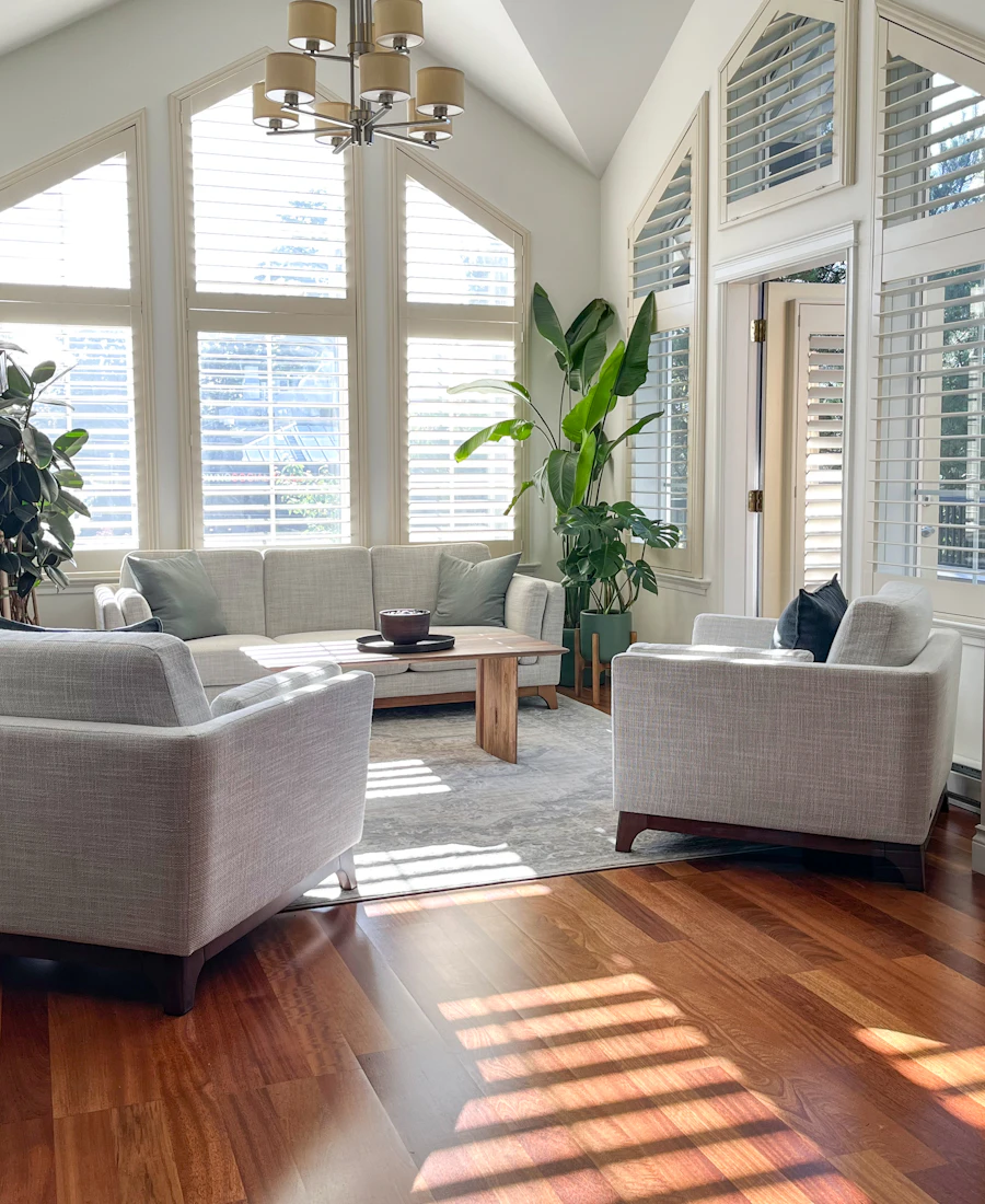 Sunny living room with tall windows and a tidy sofa