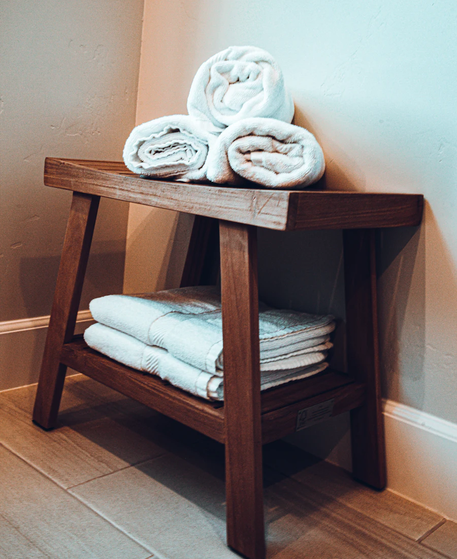 Rolled white towels on a wooden bath stool